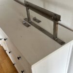Bildhalterung aus Edelstahl für ein Zweiteiliges Gemälde über zwei Wände hinweg.